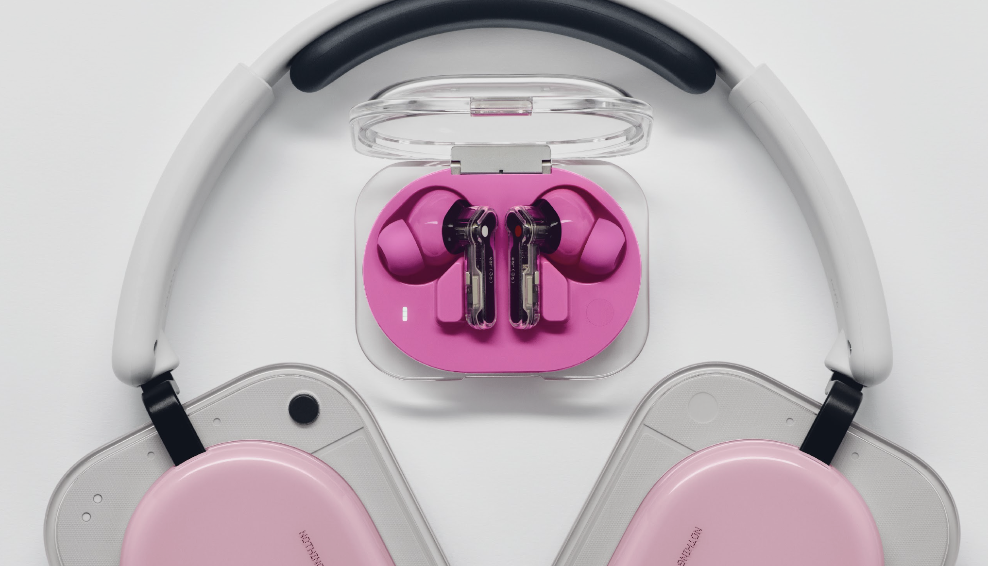 Nothing Ear (3a) on a table with Nothing Headphone (a) below, both in pink to show the difference in colorways