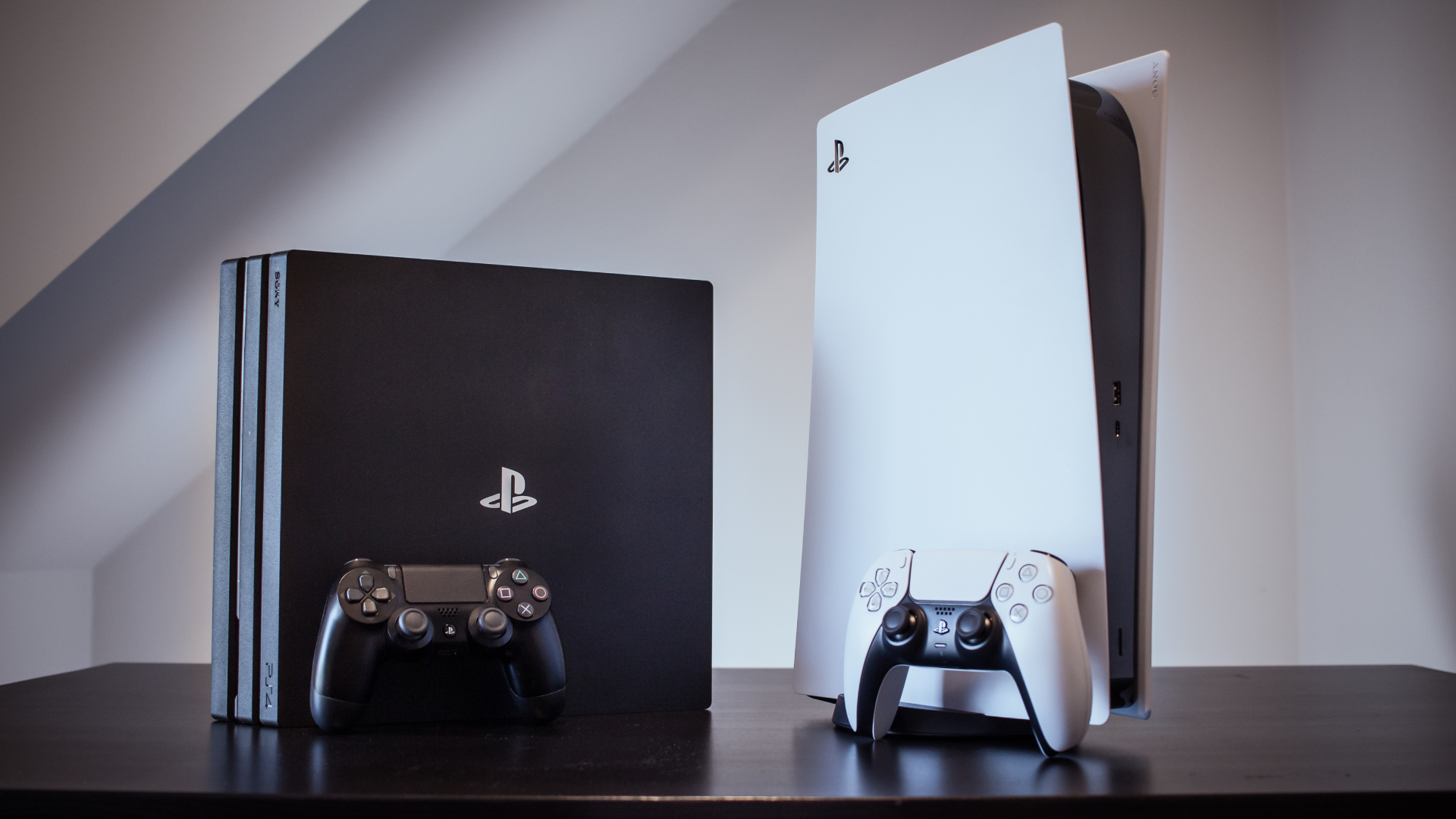 PS5 and PS4 Pro displayed on a table against a white background