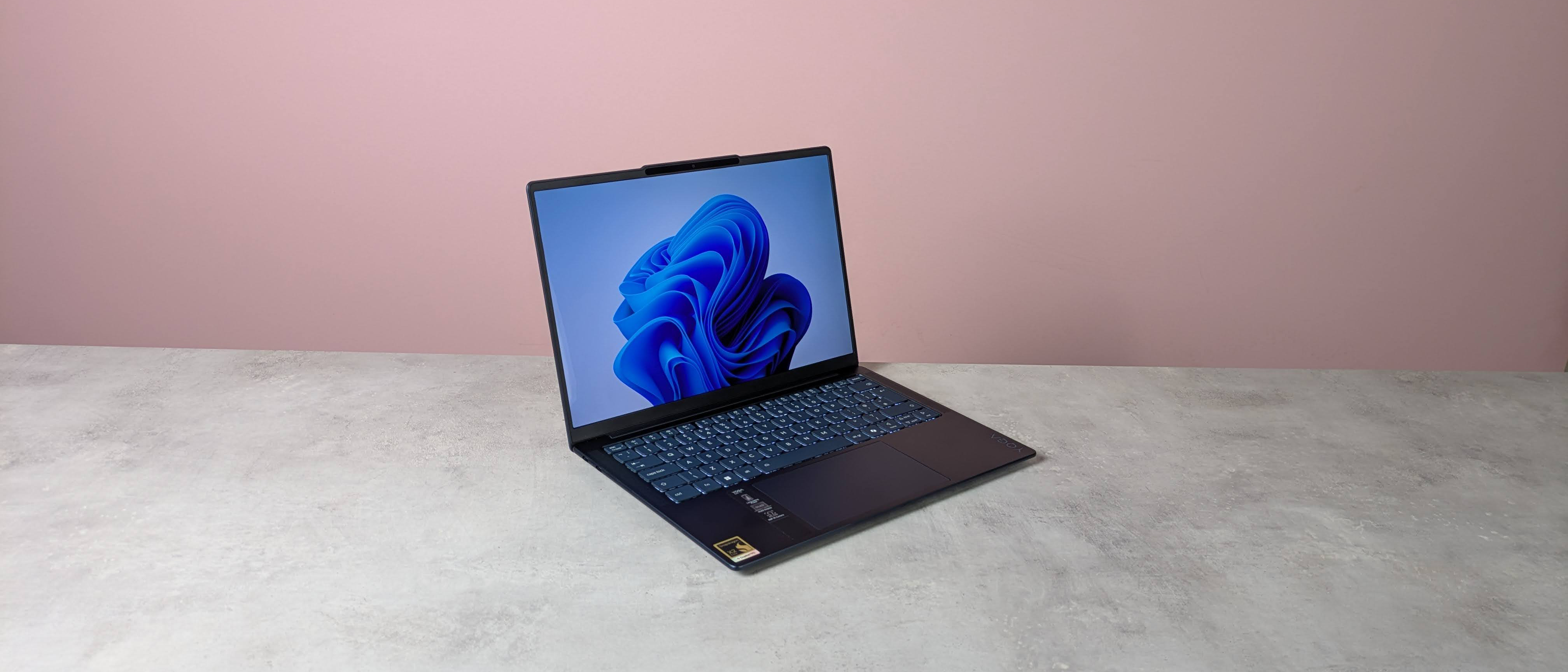 Three-quarter view of Lenovo Yoga Slim 7x Gen 11+ open on a desk with pink wall in background