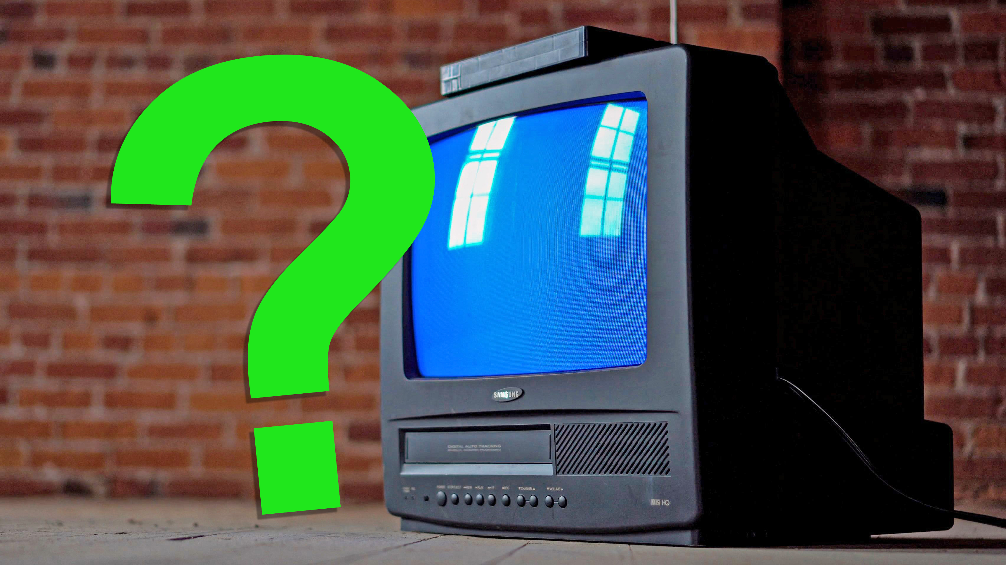 A Samsung CRT TV with a built-in VCR in front of a brick wall, with a green question mark floating over it