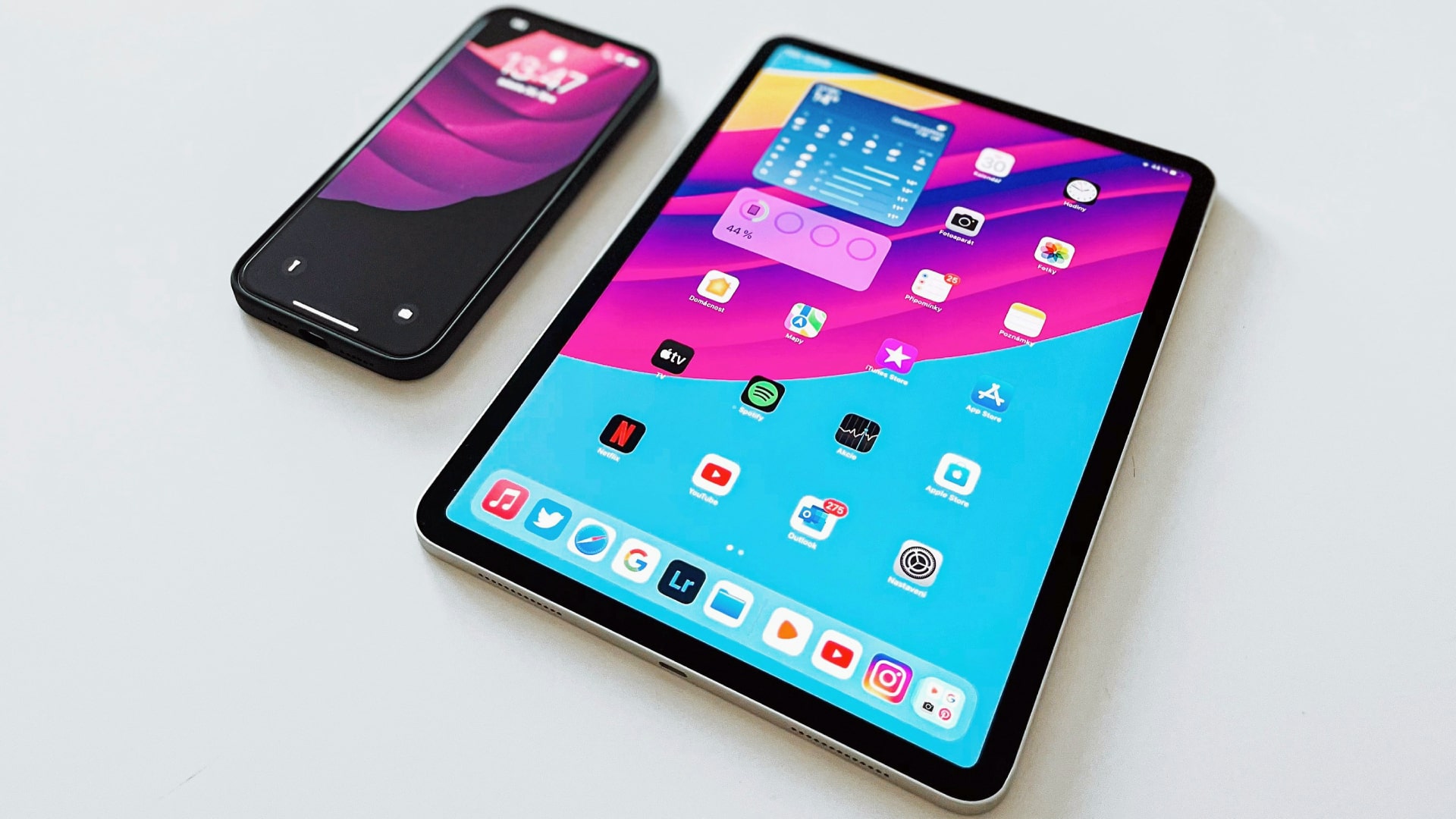 An iPhone and an iPad lying on a desk.