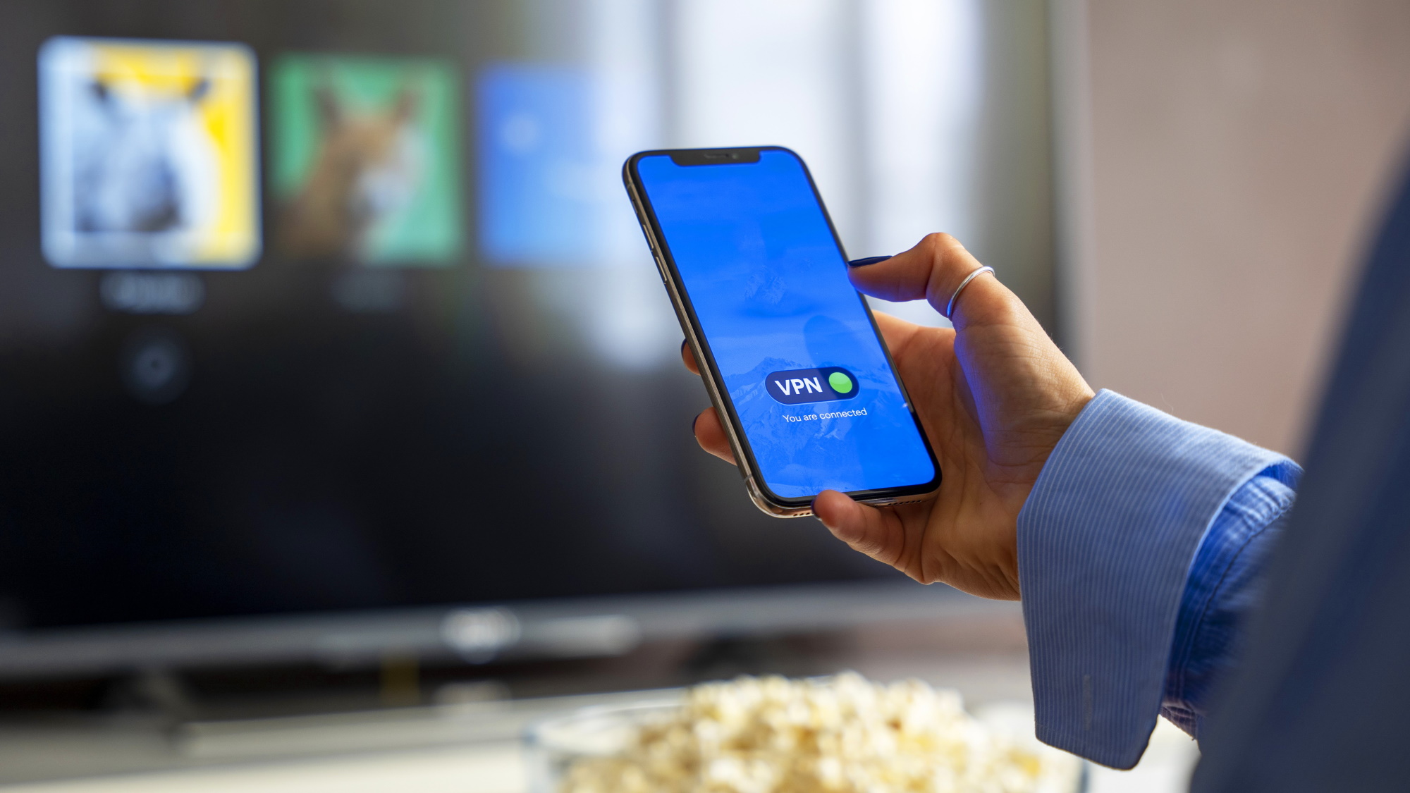 Smartphone connecting to VPN with TV screen blurred in the background