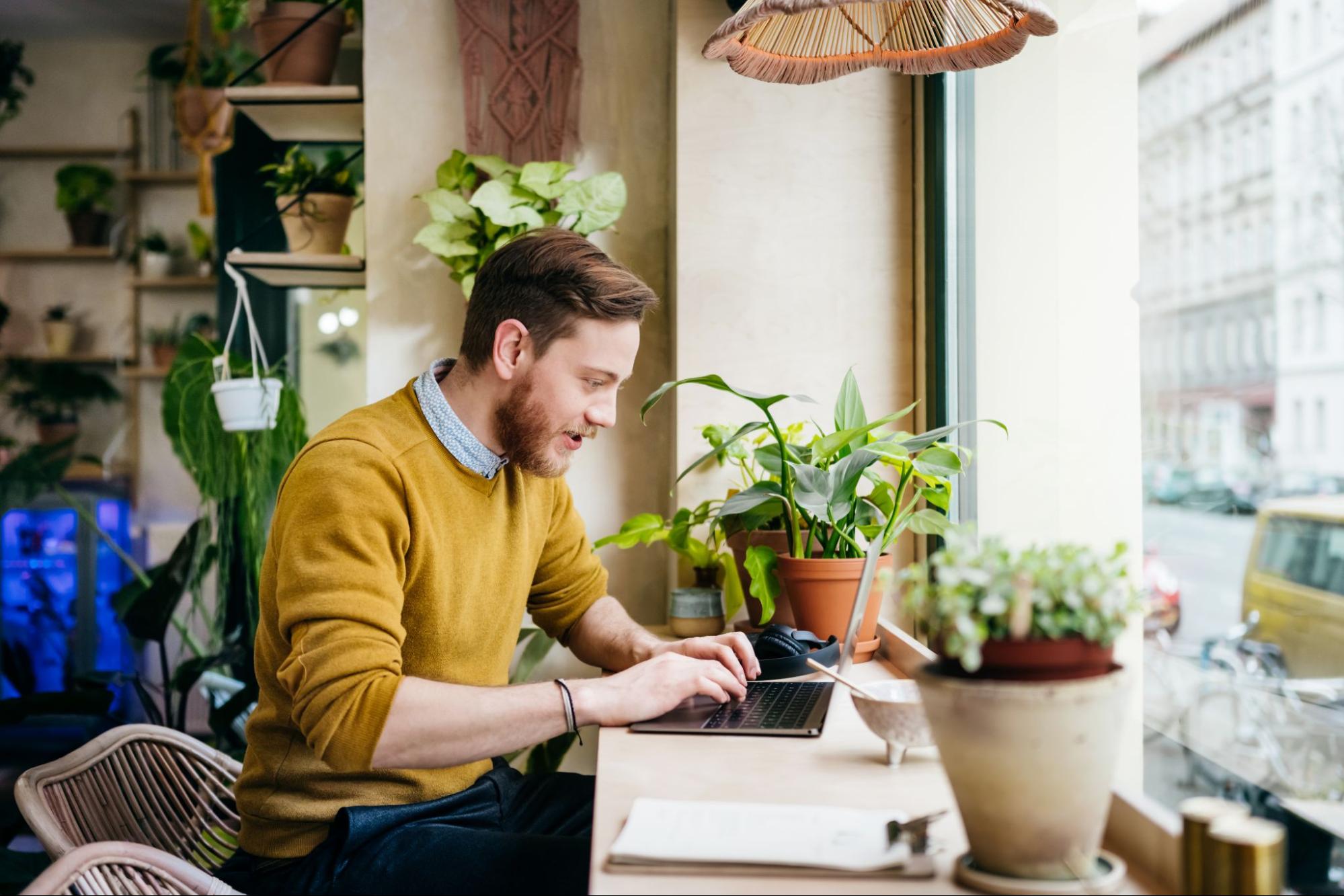 Man working on laptop by a window