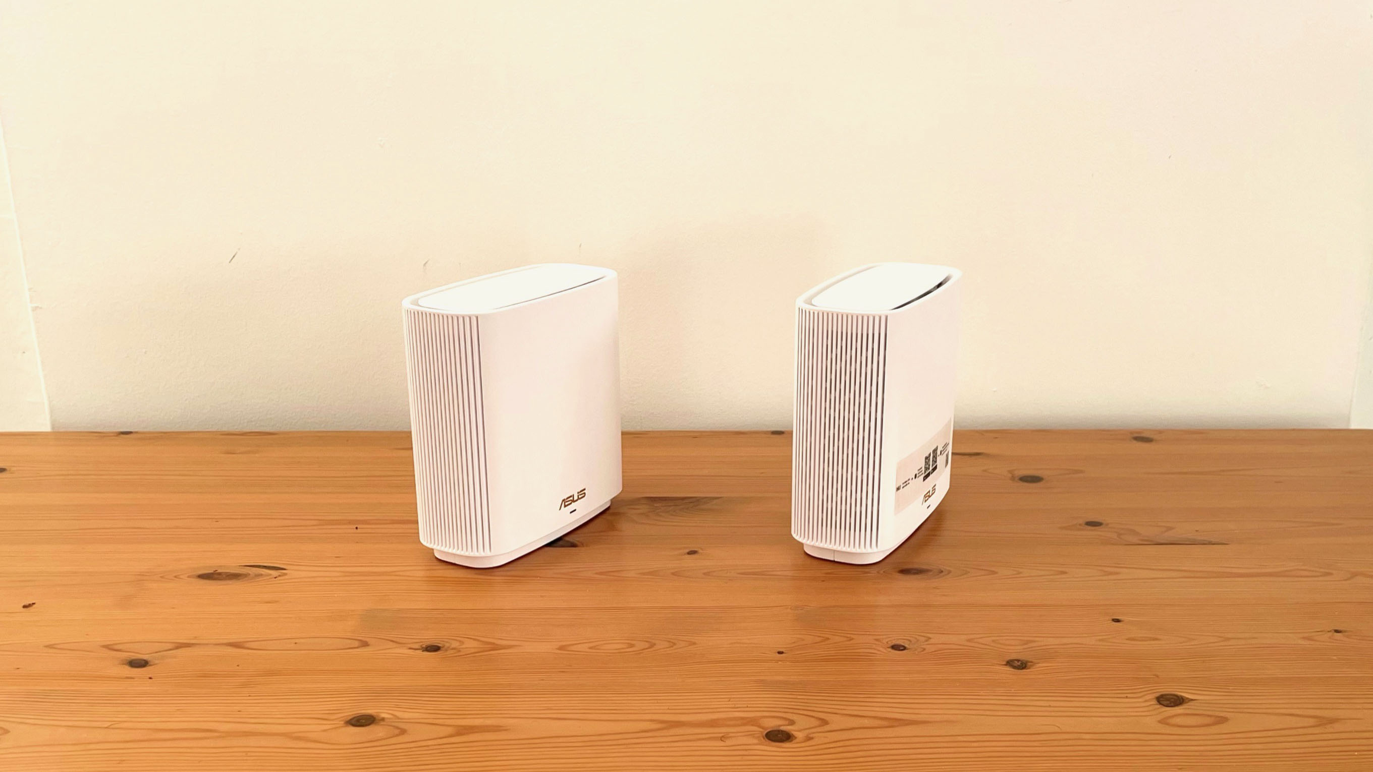 Asus ZenWifi XT9 product review images on a wooden desk