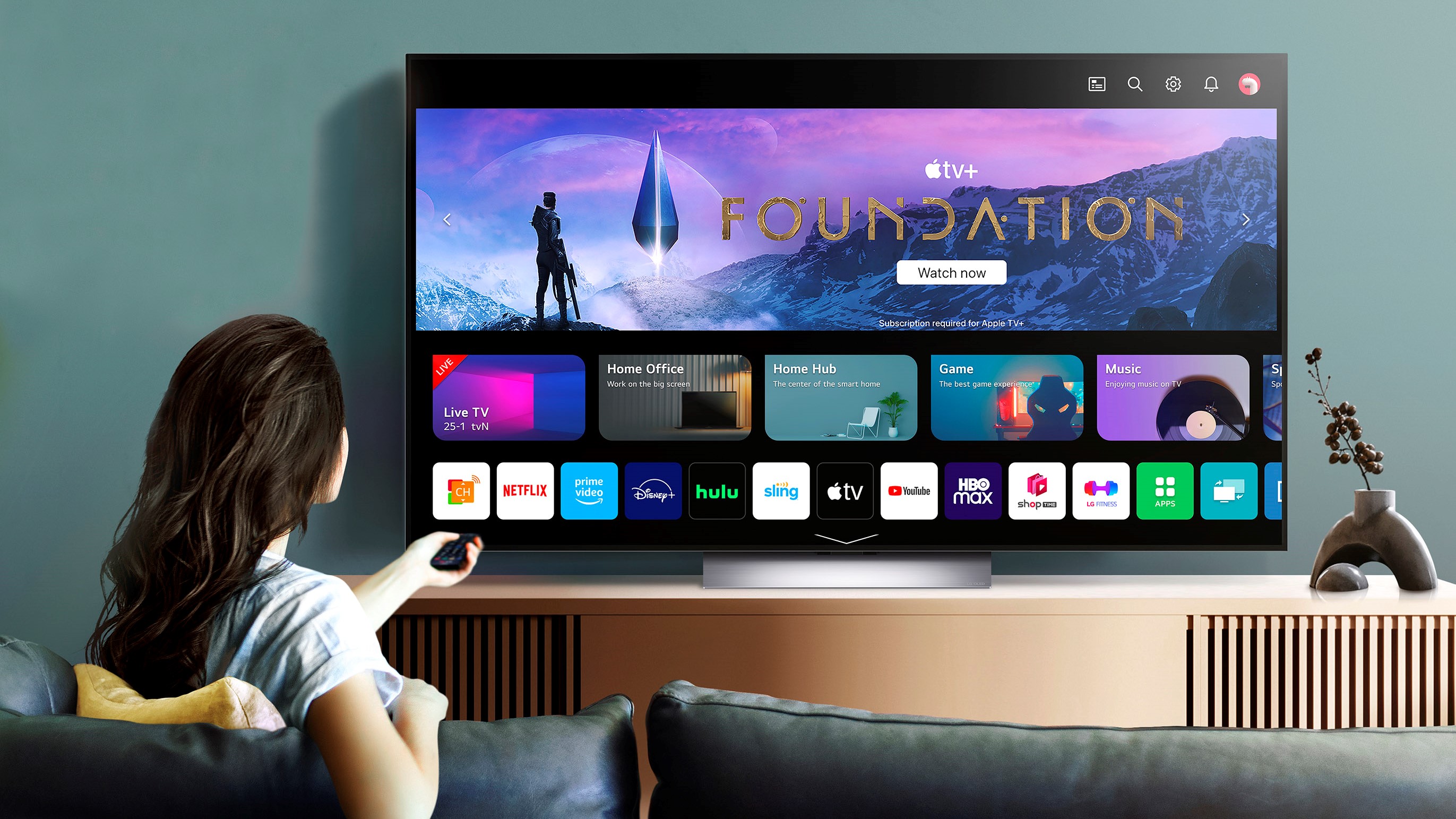 A woman sat in front of an LG C3 OLED TV in a bright living room.