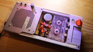 A silver device with a speaker and cassette visible, plus some physical controls and an orange dial