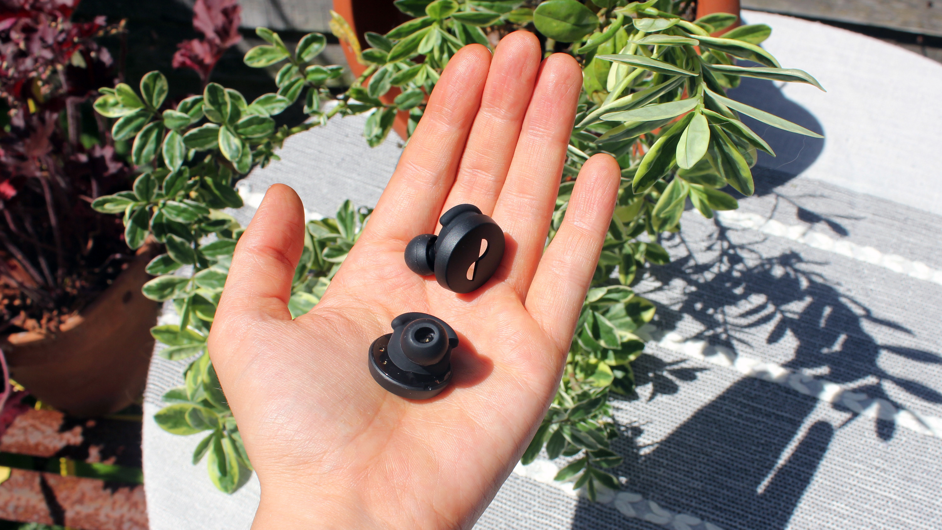 a open palm holding the the nuratrue earbuds