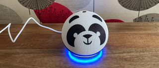 The Amazon Echo Dot Kids smart speaker on a wooden table with a patterned background