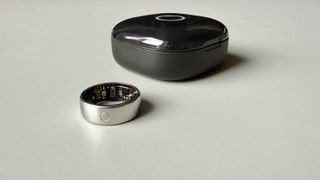 The Circular Ring 2 smart ring pictured next to its charging case on a grey surface.