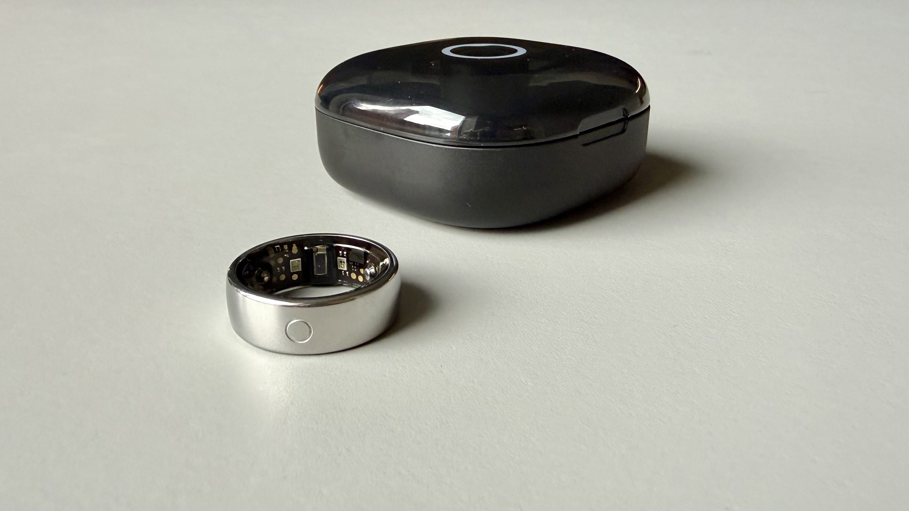 The Circular Ring 2 smart ring pictured next to its charging case on a grey surface.