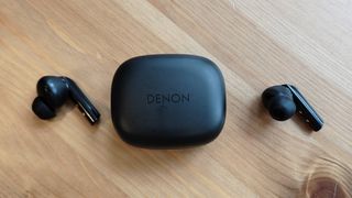 The Denon AH-C840NCW against a wooden table.