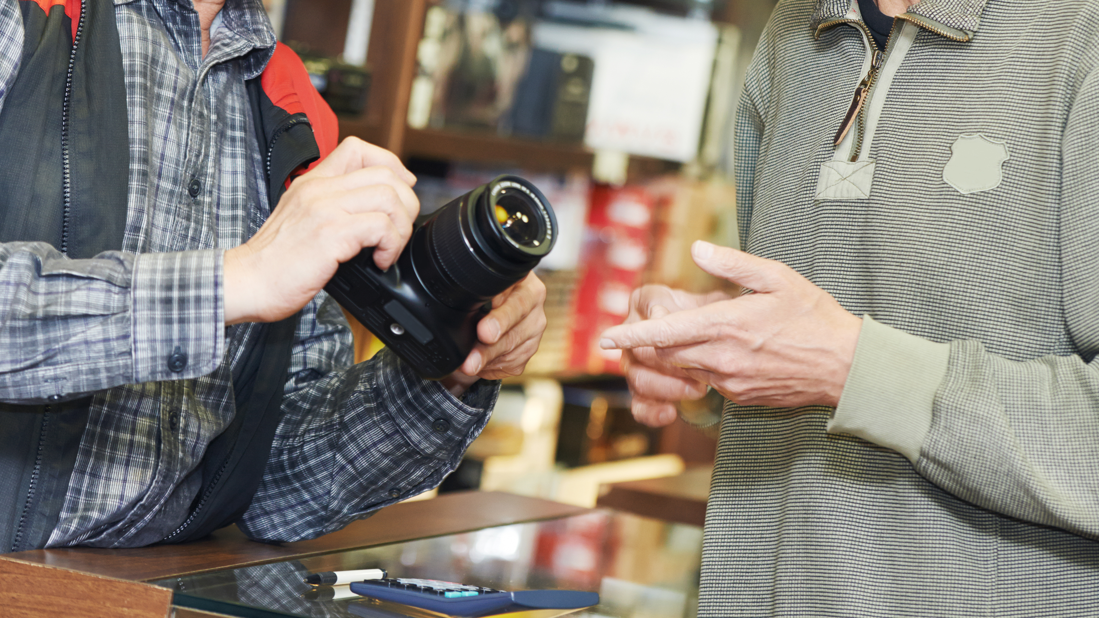 Assistant seller help buyer by demonstrating digital photo camera at shop store