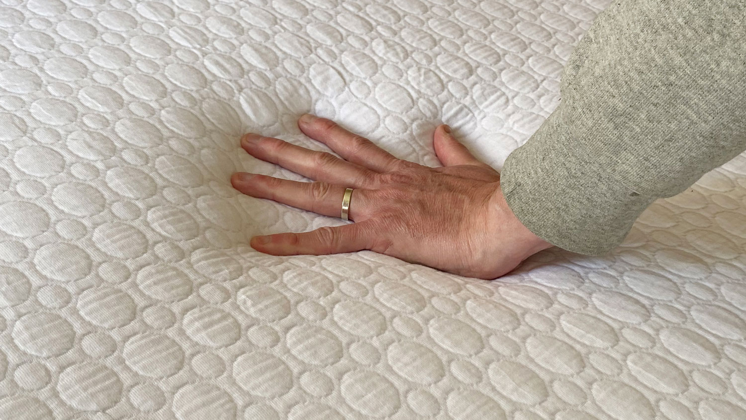 A hand pressing down on the Simba GO Hybrid mattress