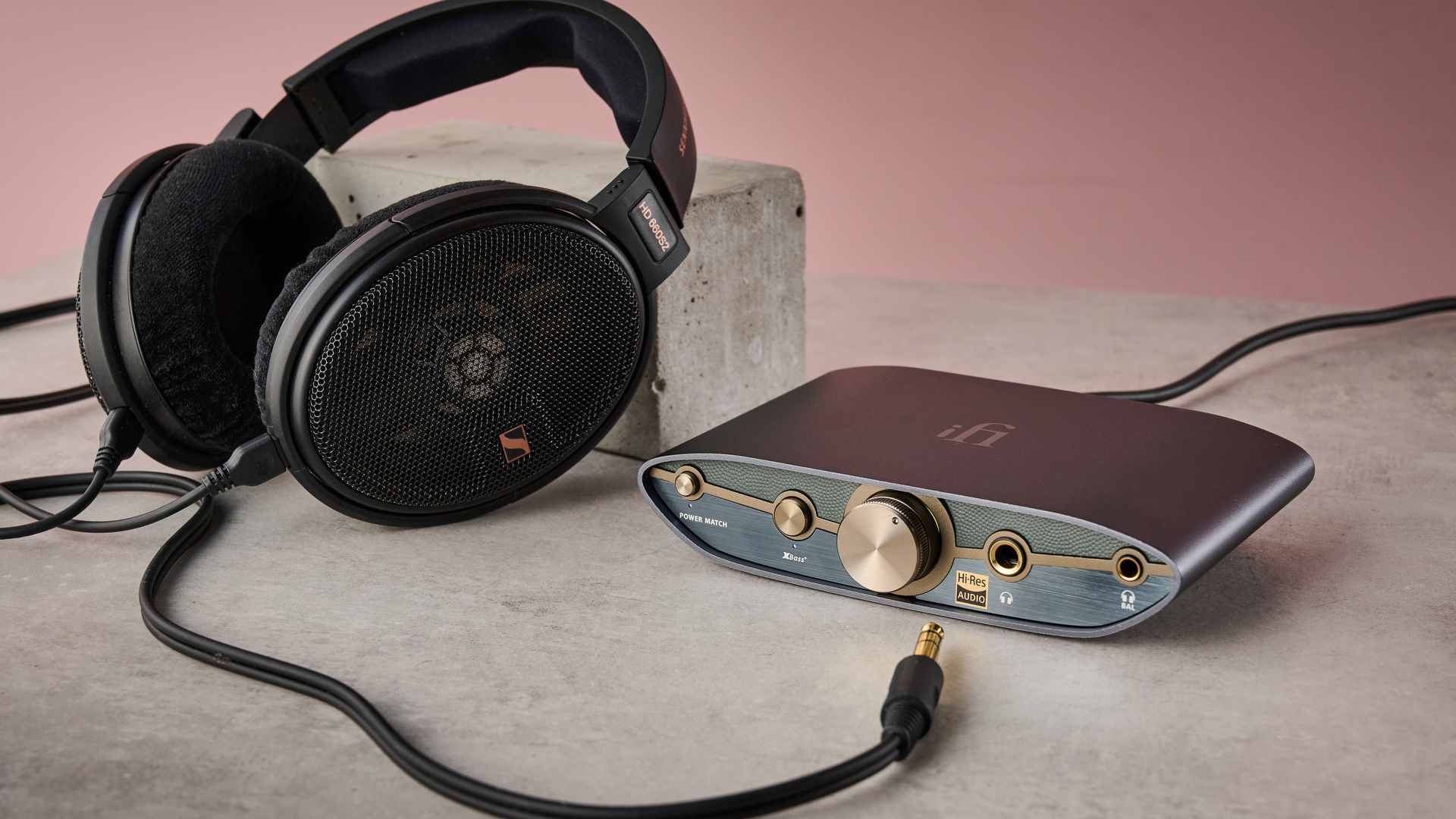 The Sennheiser HD 660S2 leaning against a concrete block next to the iFi Zen DAC 3, with the wire not plugged in.