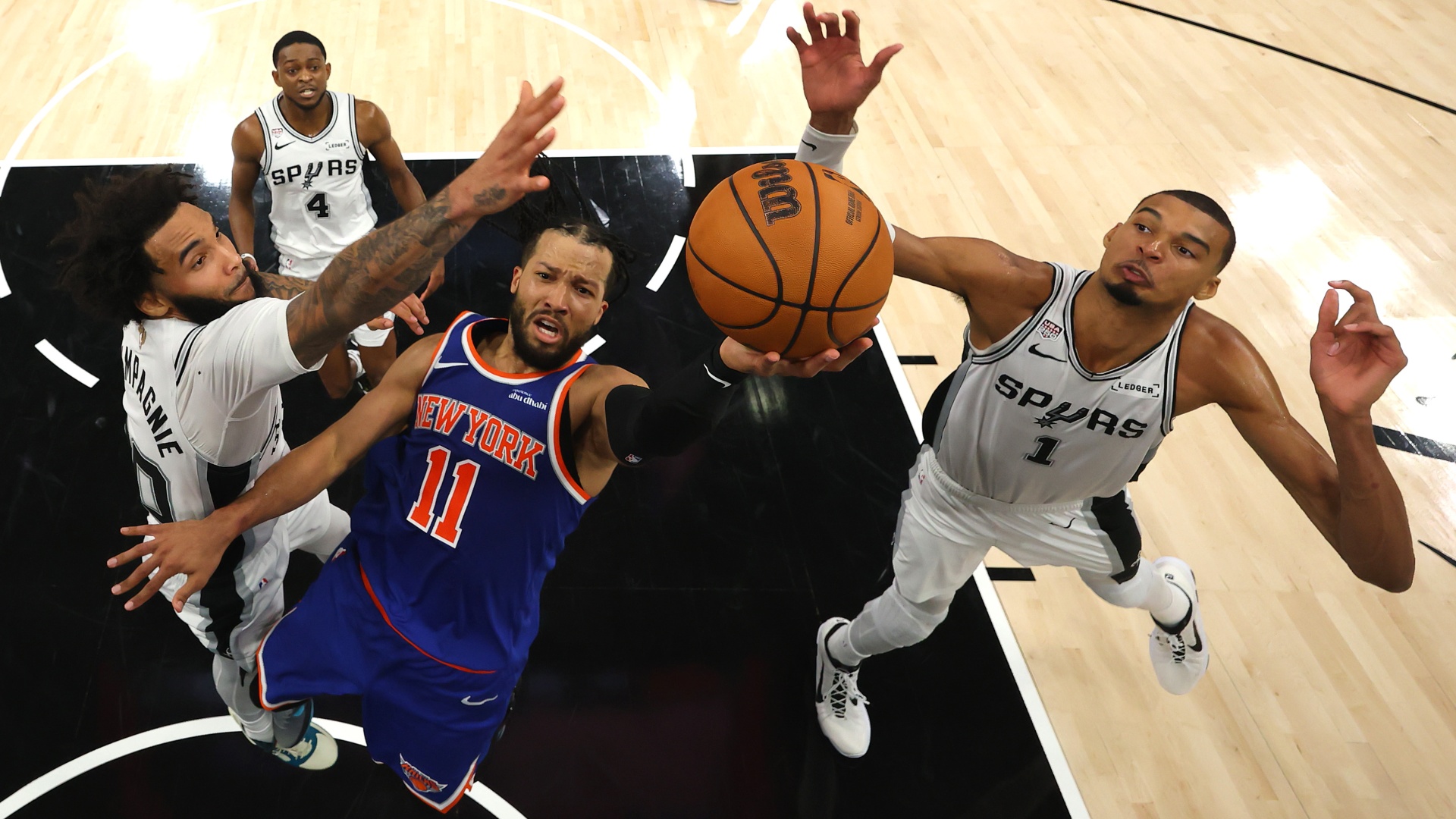 Jalen Brunson of the New York Knicks shoots the ball between Julian Champagnie and Victor Wembanyama of the San Antonio Spurs in the 2026 NBA Finals