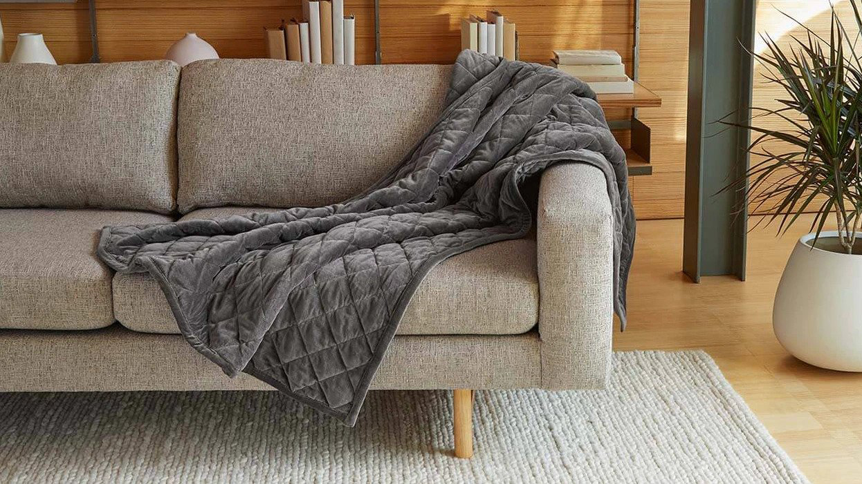 Best weighted blankets: weighted blanket draped over the arm of a sofa