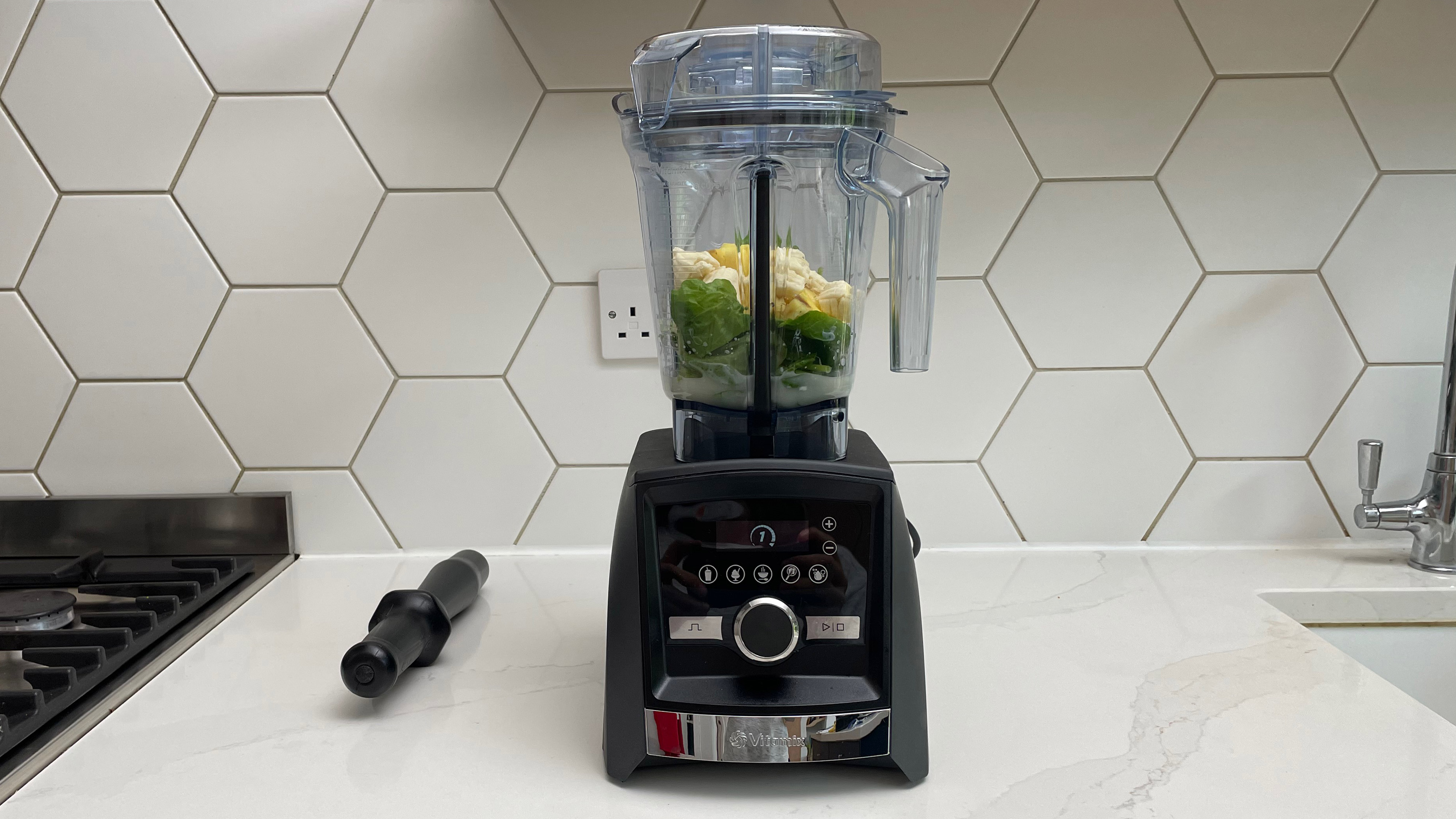 The Vitamix A3500 filled with pineapple and spinach on a kitchen countertop