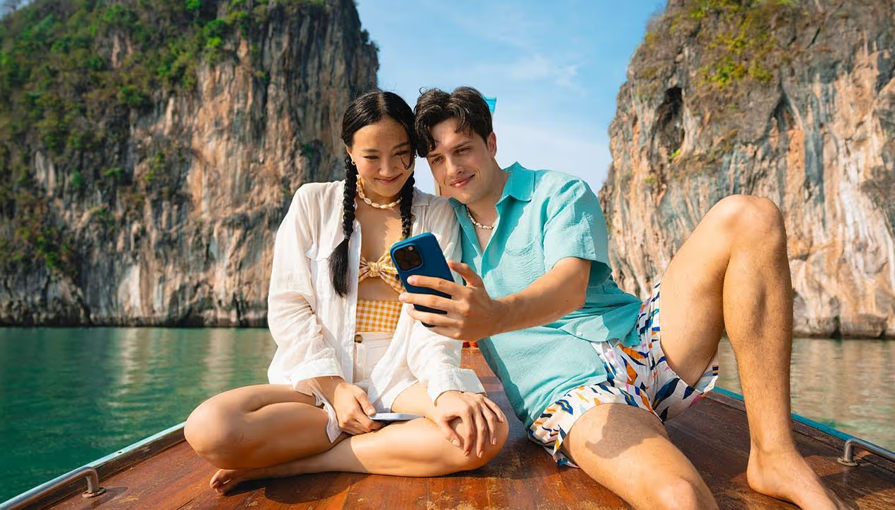 A couple on a body of water, looking at their phone.