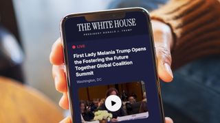 A hand holding a phone showing The White House app