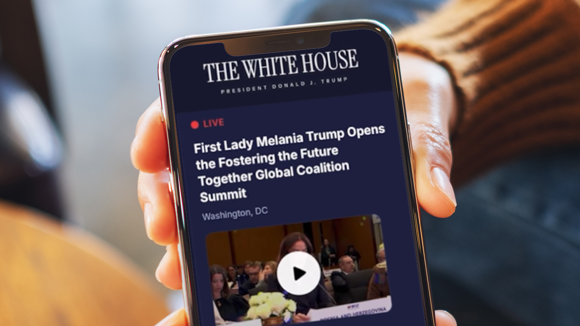 A hand holding a phone showing The White House app