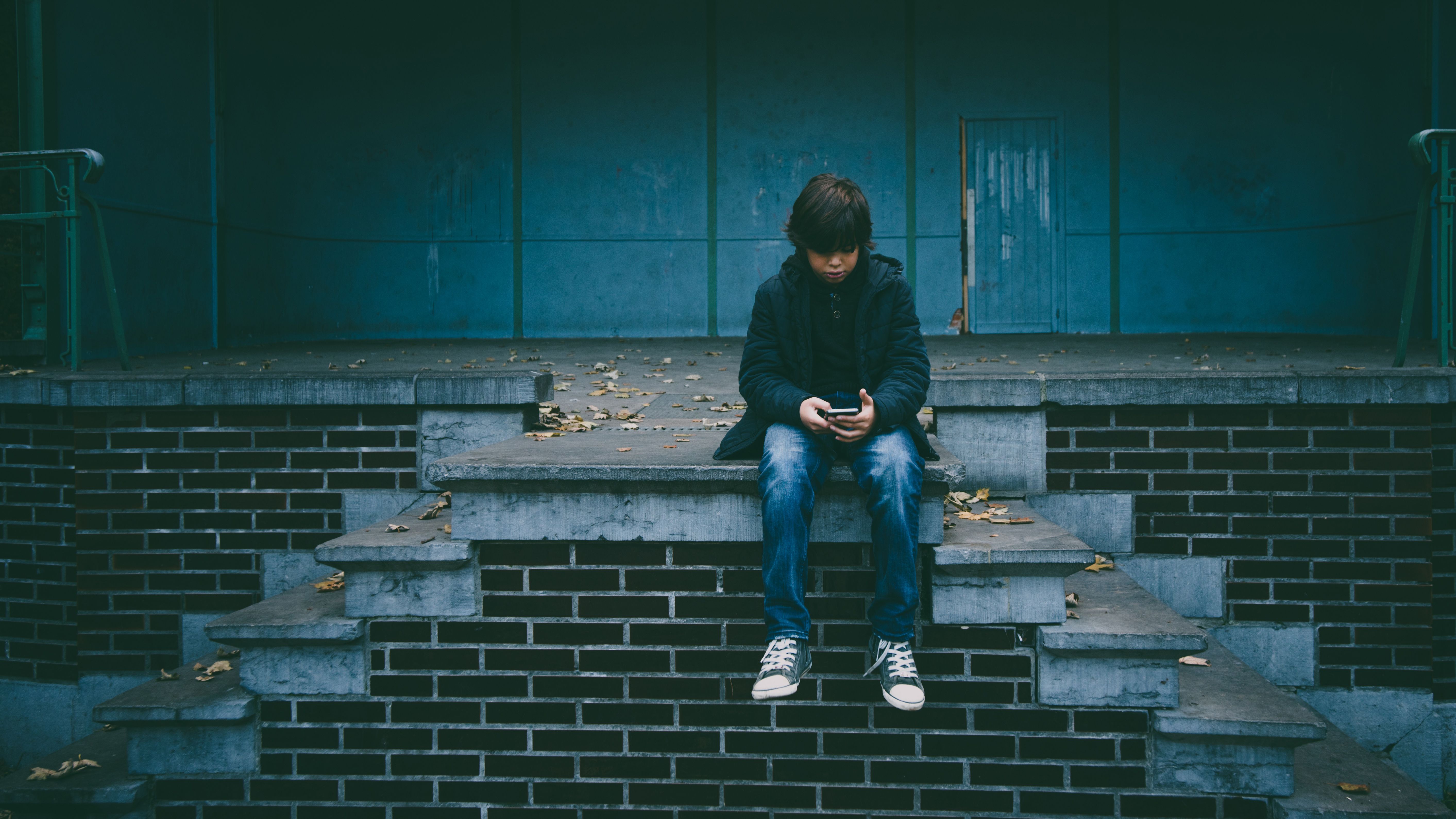 Child sitting on stairs looking at phone