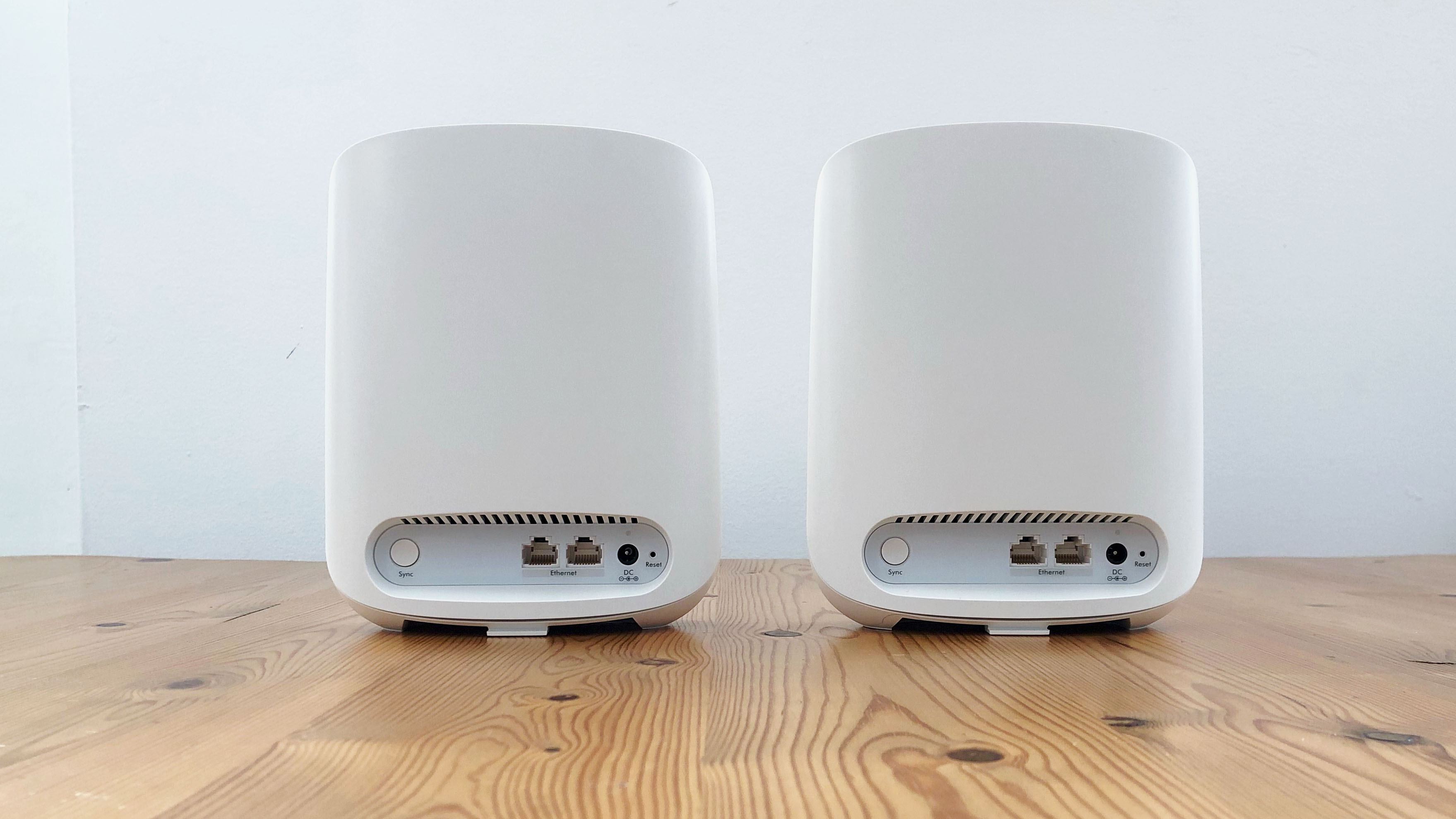 Netgear Orbi RBK353 on a wooden table in front of a white background