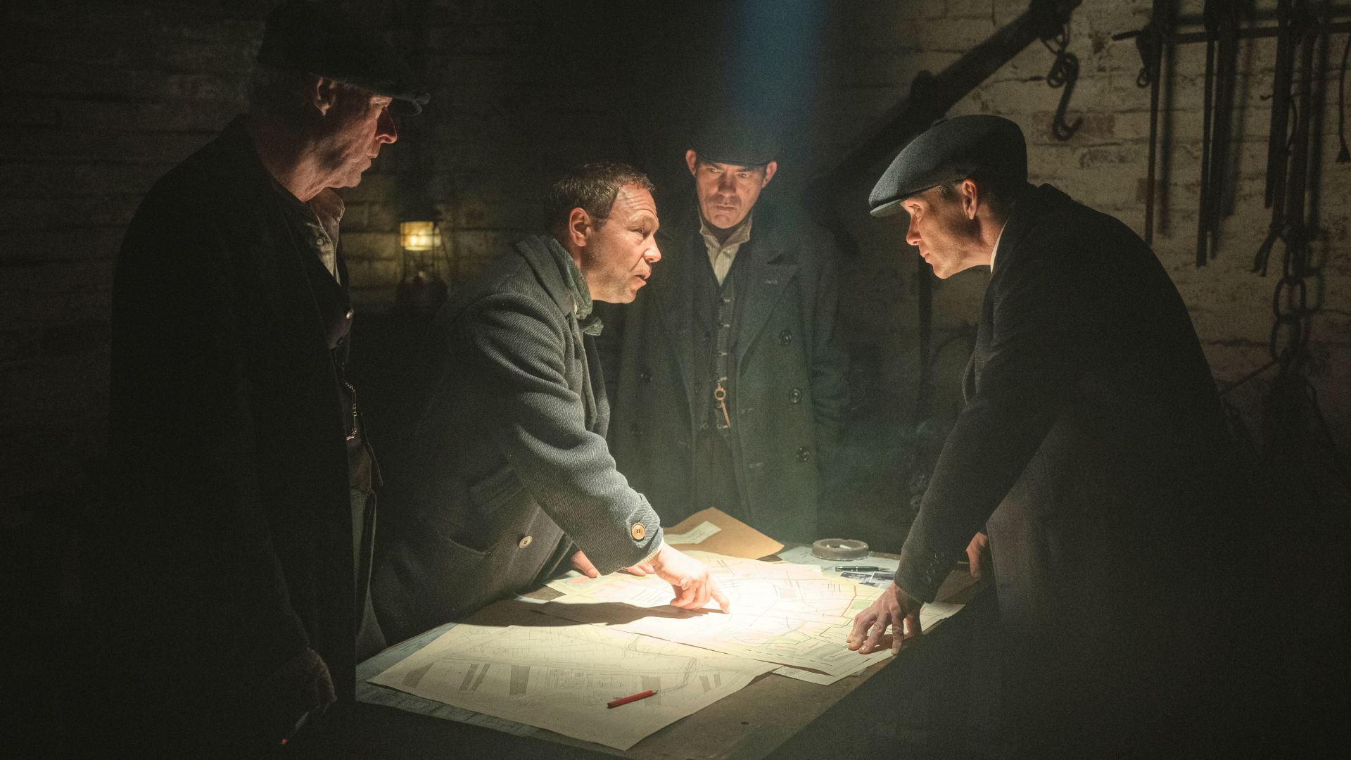 The Peaky Blinders gather around a dimly lit table