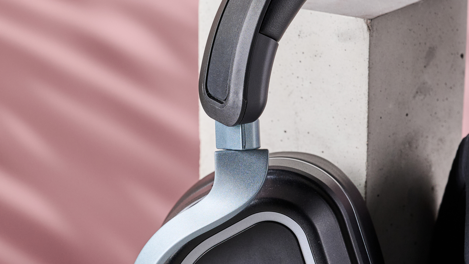 Close-up of driver hinge on Turtle Beach Stealth 700 Gen 3, leaning on plinth with pink background