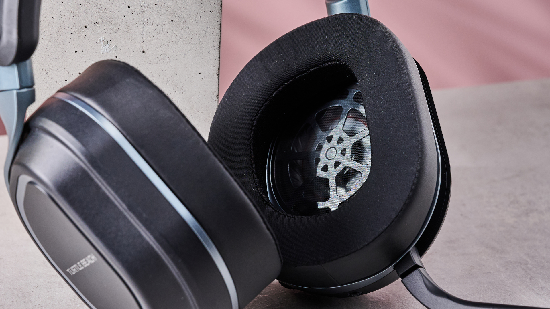 Close-up of inside of driver of Turtle Beach Stealth 700 Gen 3, leaning on plinth on desk with pink background