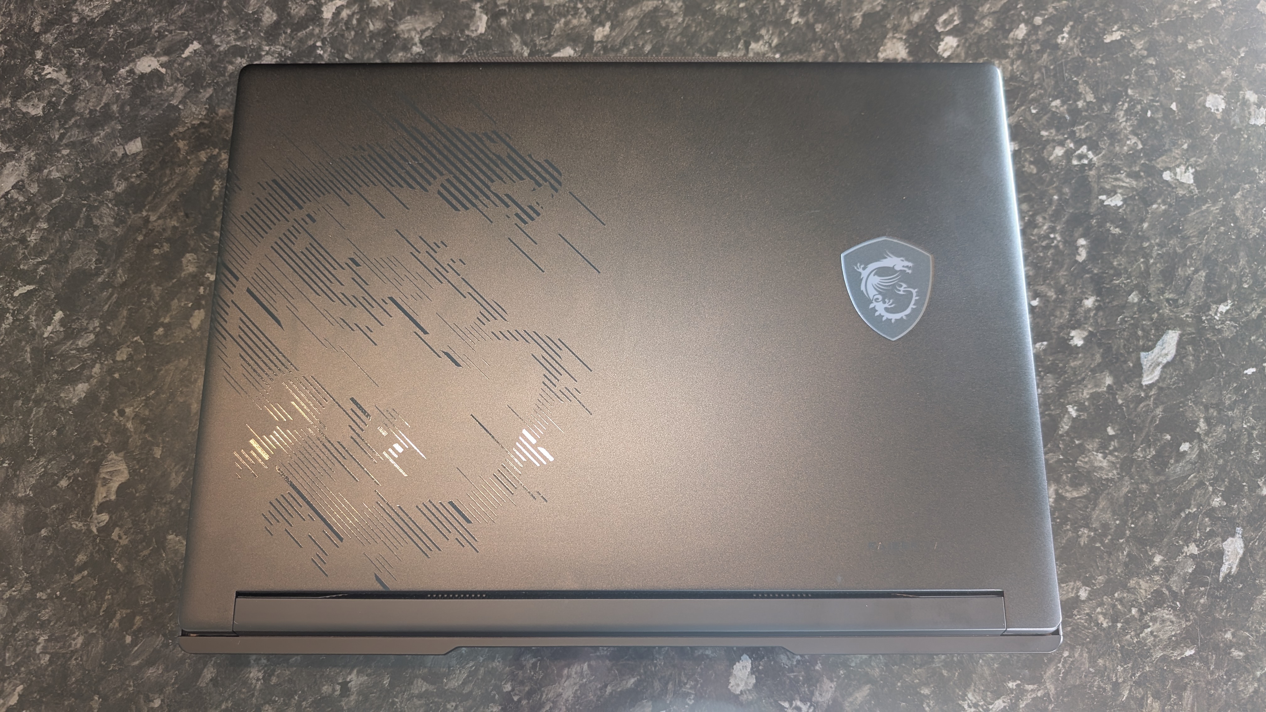 The MSI Raider 16 Max HX gaming laptop pictured on a black marble worktop.