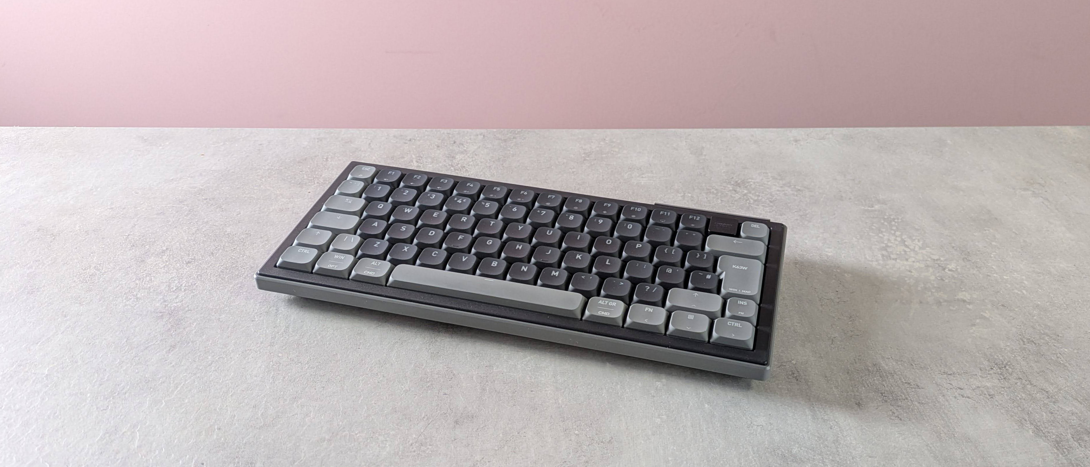 Cherry XTRFY K63W Pro Compact Ultra-Wideband on desk with pink wall in background
