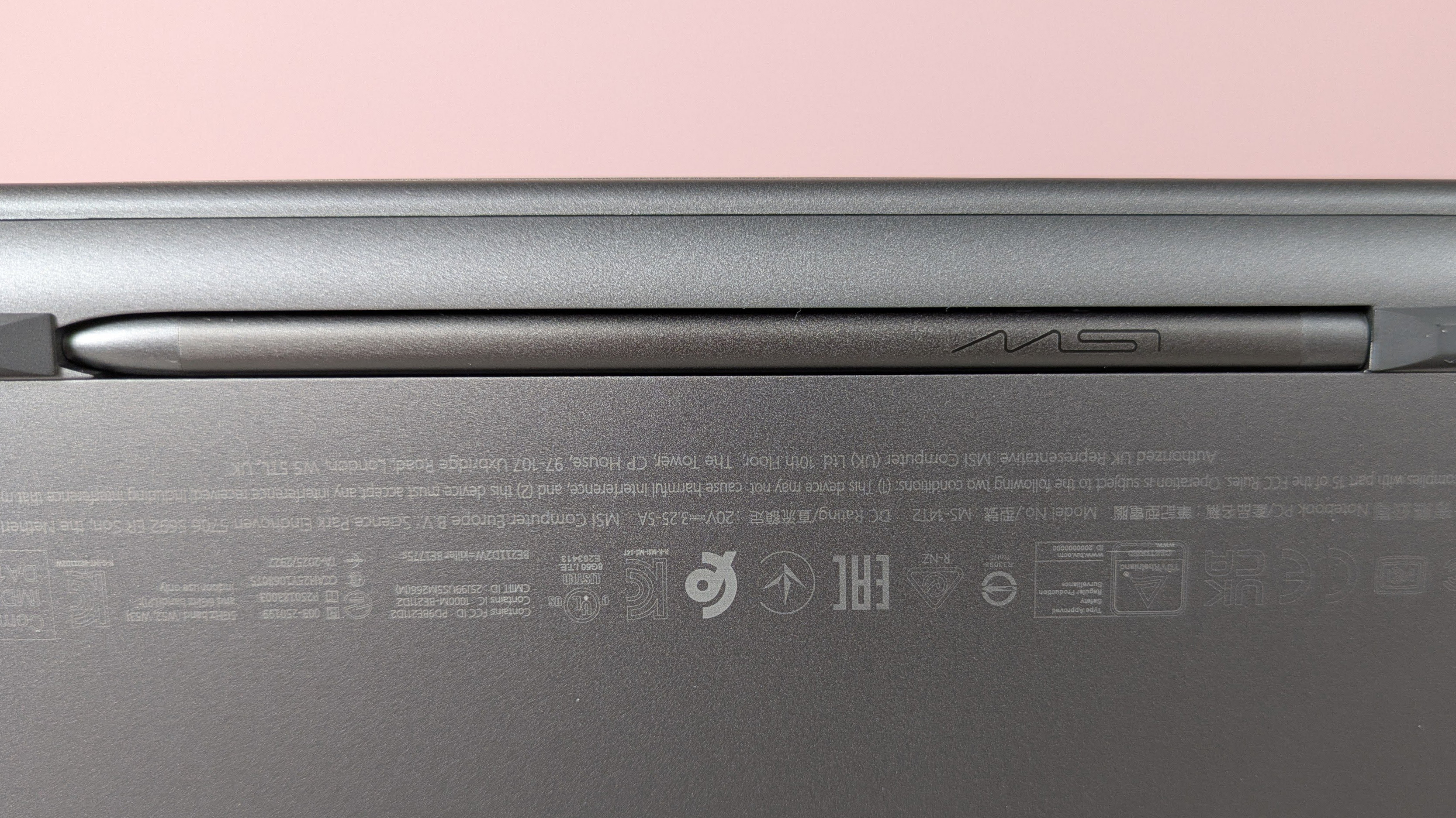 Close-up of MSI Nano Pen in compartment underneath MSI Prestige 14 Flip AI+, with pink wall in background