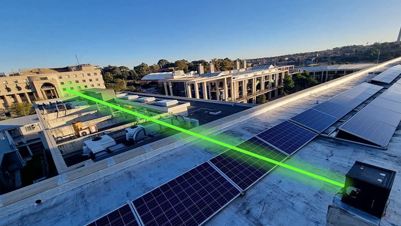 A green beam of light is fired  from an internet device on a rooftop.
