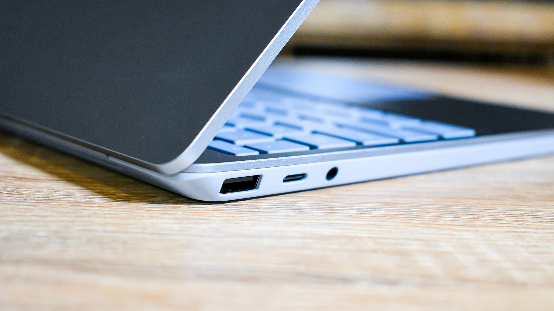 A half open Surface Laptop Go turned away and sitting on a wooden desk