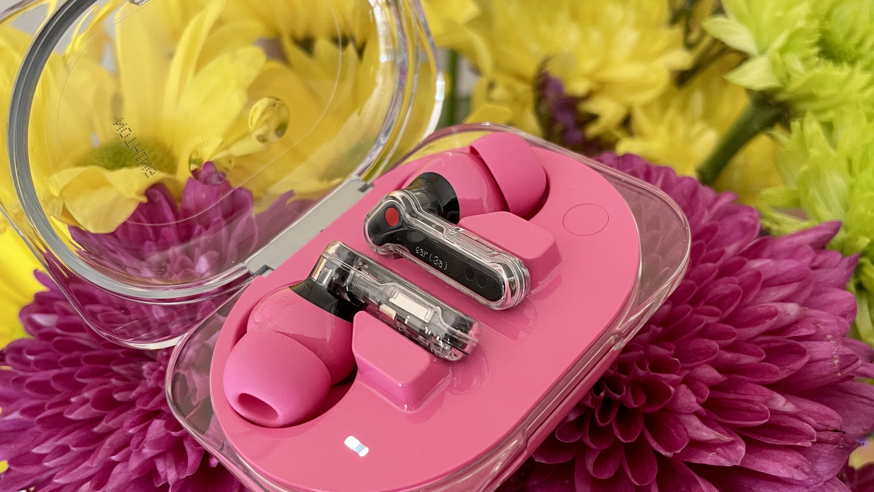 Nothing Ear (3a) on a floral background, with pink, red and yellow flowers