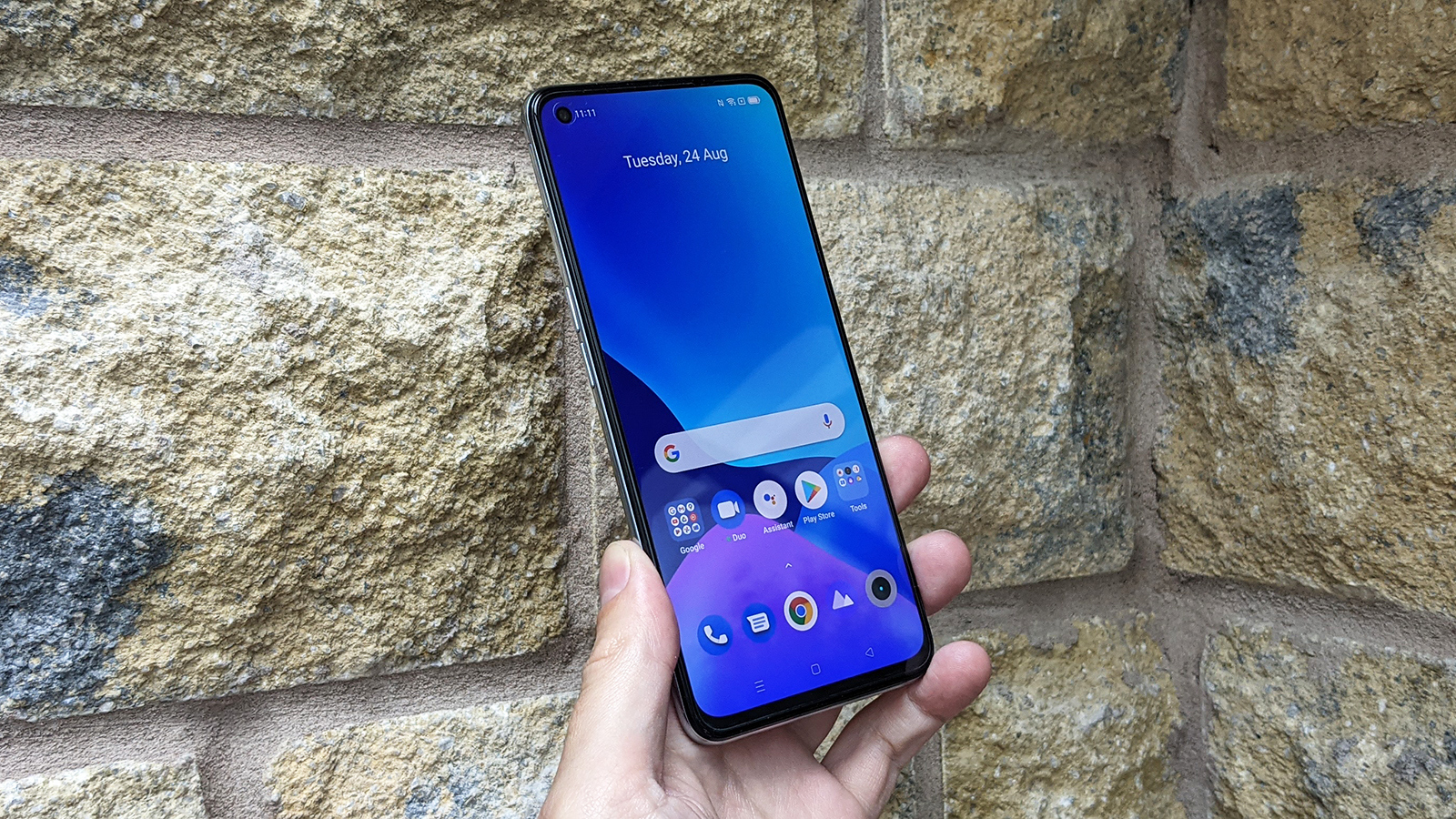 The Realme GT Master Edition facing forwards being held in someone's hand.