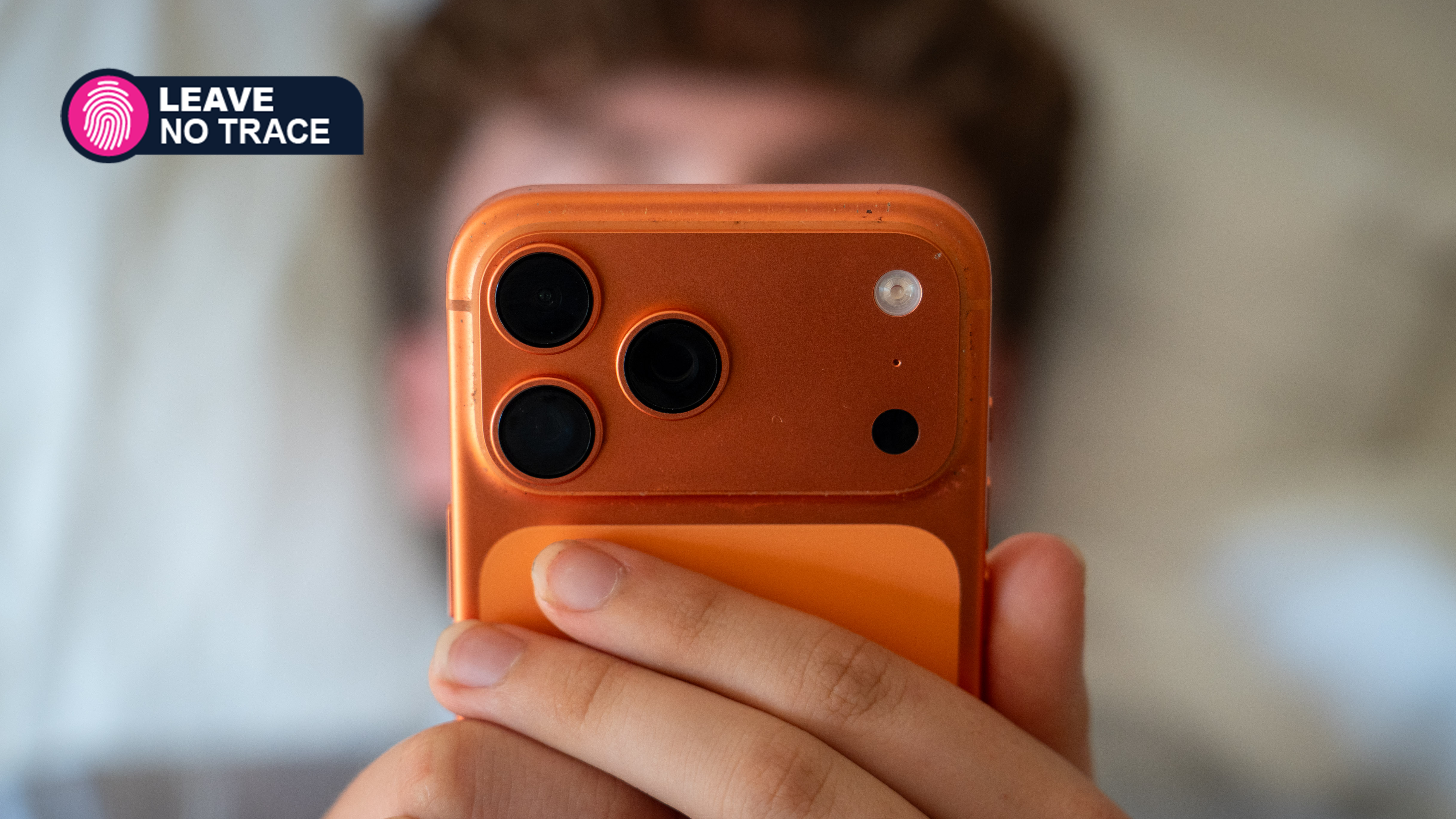 Guy looking at an orange iPhone screen in his bedroom, Leave No Trace logo on top left