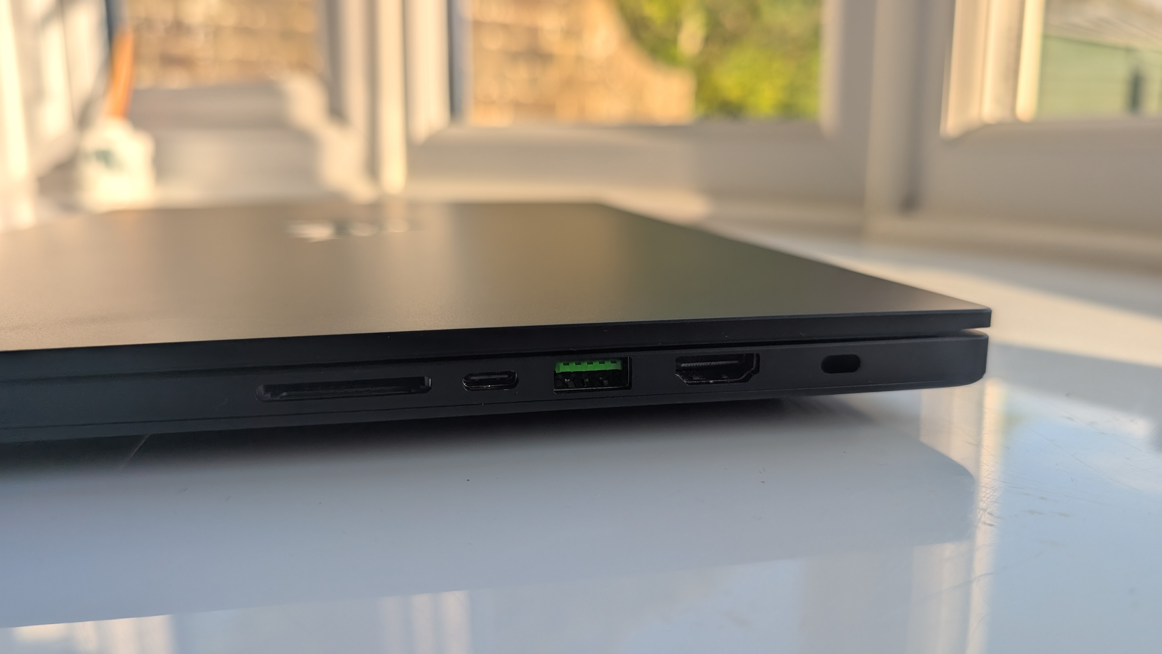 The Razer Blade 16 photographed for TechRadar on a white surface with plants in the background.