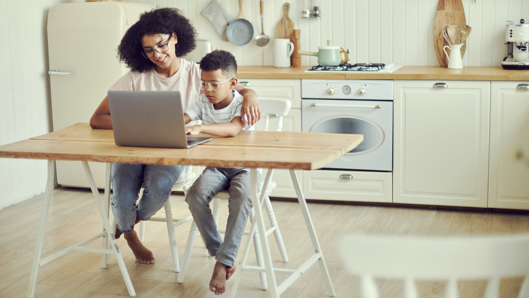 Parent with a child using a laptop in the kitchen
