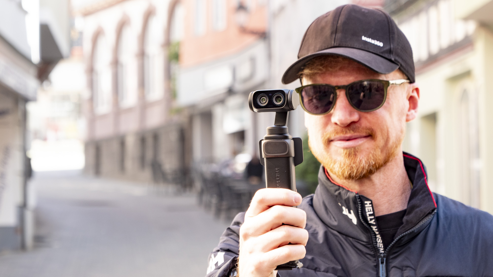 Man holding the Insta360 Luna Ultra vlogging camera on a sunny day in a old town