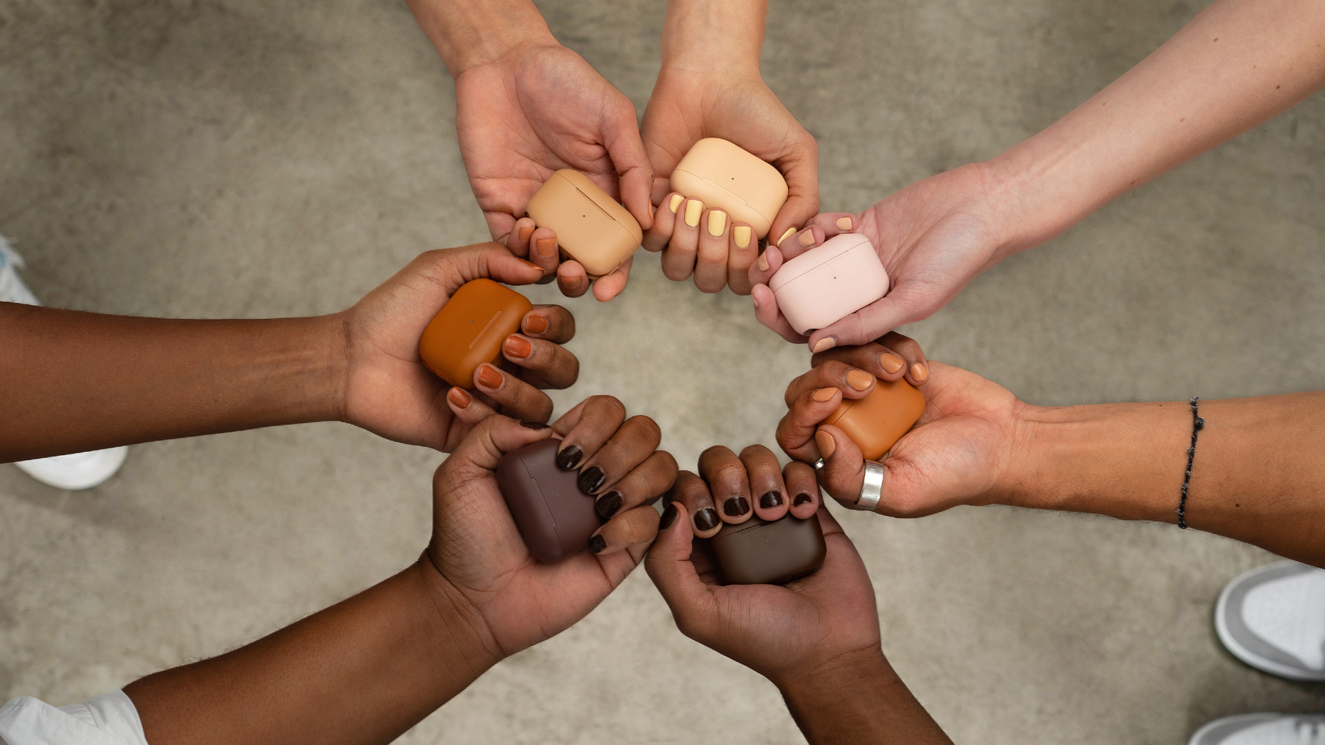 JLab Go Air Tones held by hands on a beige background