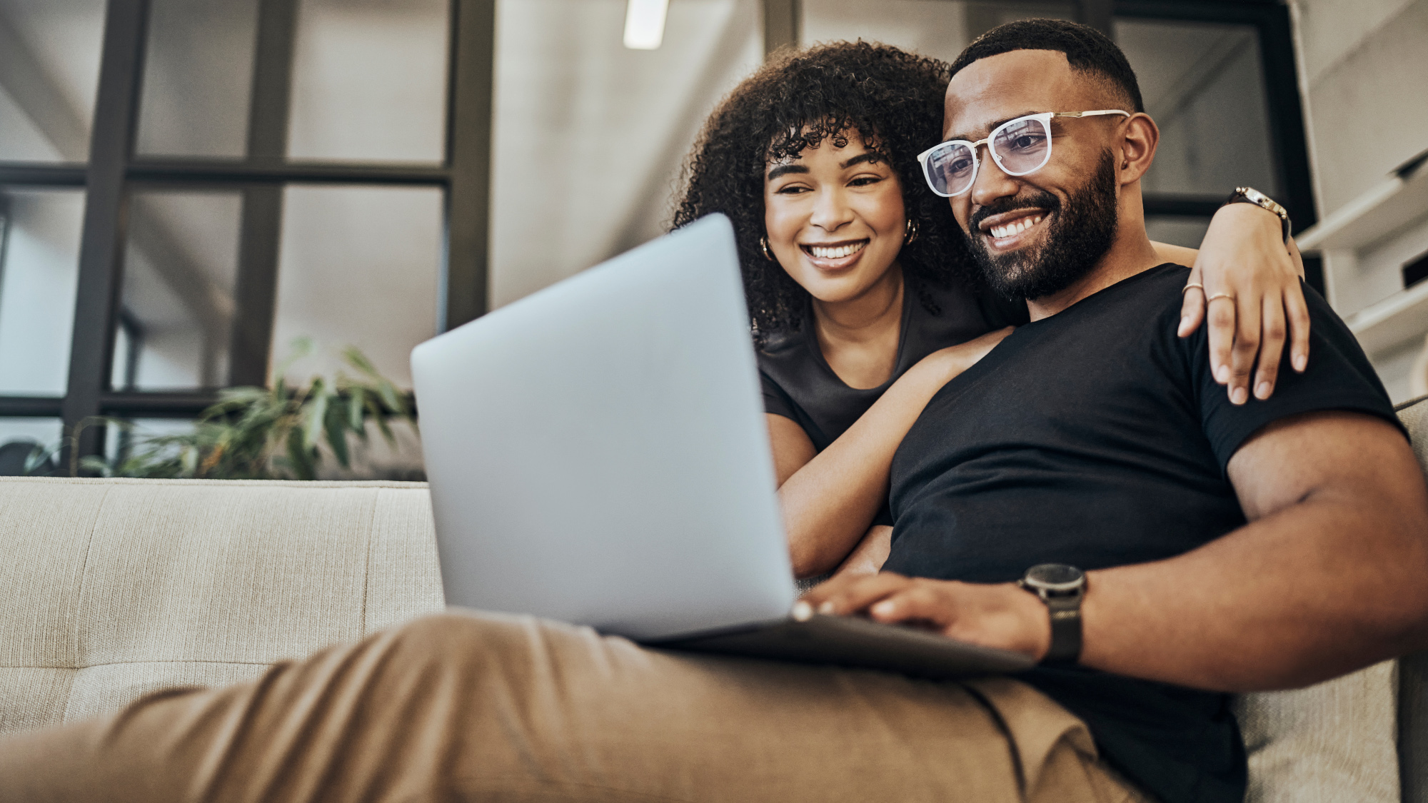 A couple using a laptop, smiling