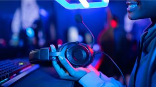 A young gamer holding a gaming headset in their hand