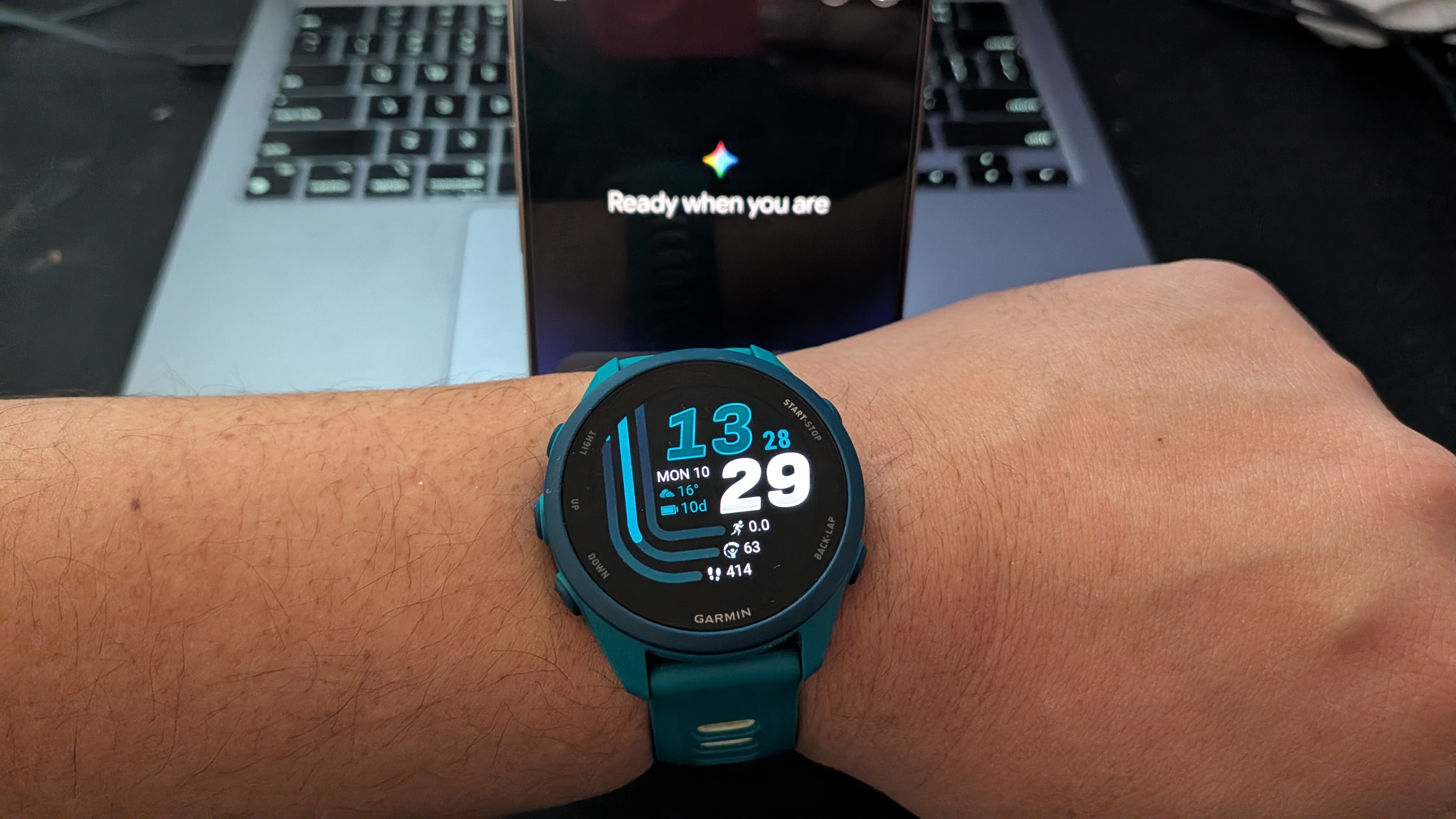 A Garmin Forerunner 170 Music worn with a phone with Google Gemini's splash page