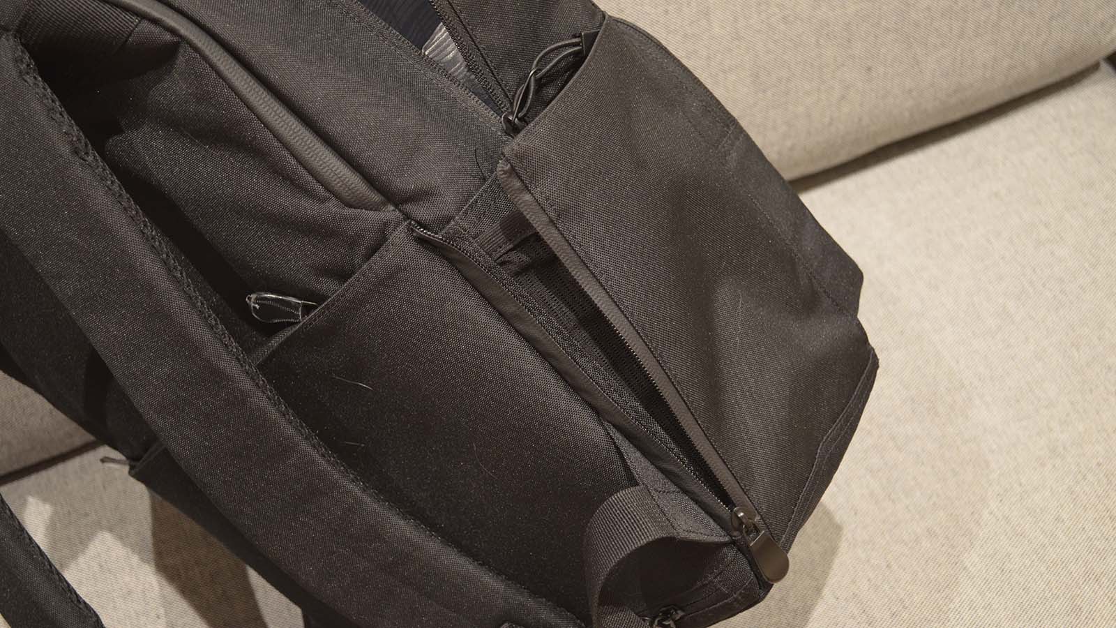 A Lo &amp;amp; Sons Hanover Deluxe 2 backpack laying on its side on a gray couch