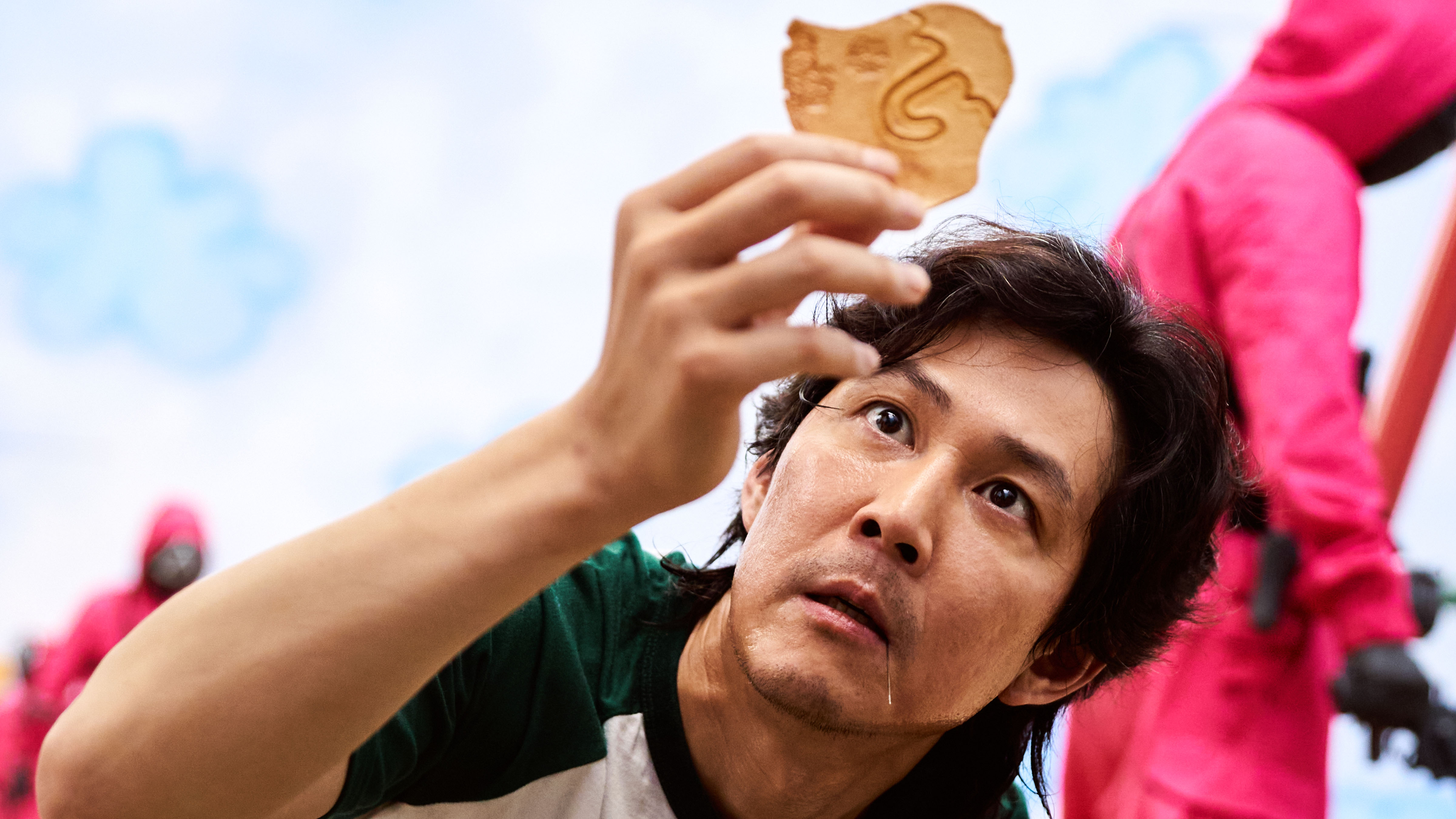 Gi-hun looking carefully at an umbrella cookie in Squid Game.