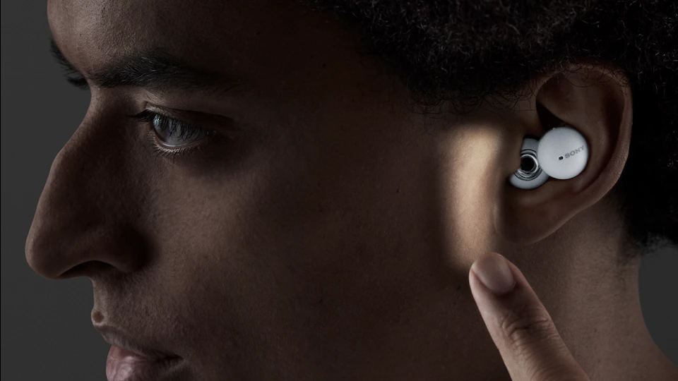 Man reaching finger towards ear to tap earbud