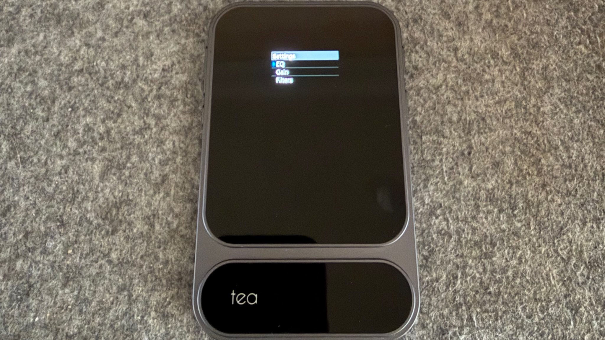 Photograph of the Khadas Tea Pro Headphone Amplifier on a grey fabric surface