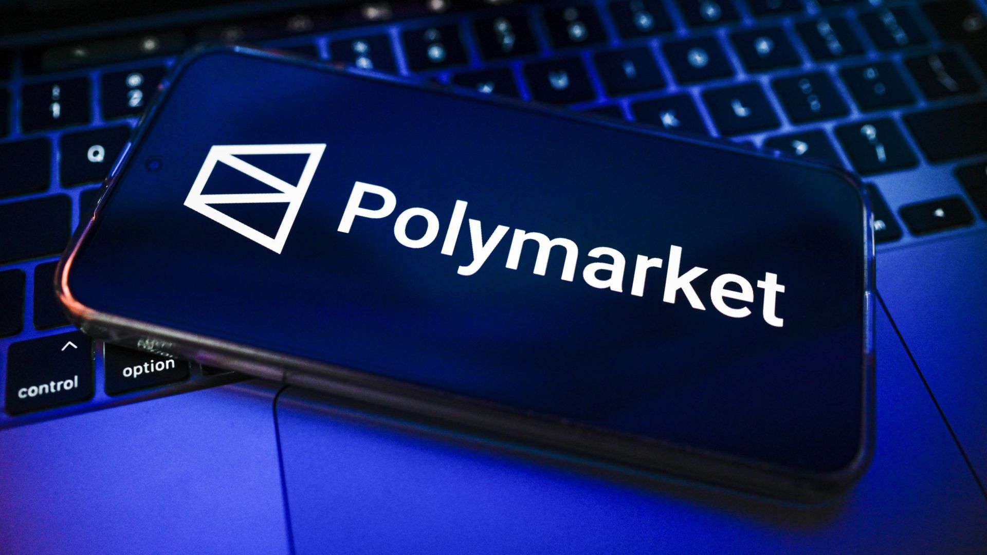 Polymarketlogo on smartphone, on laptop keyboard