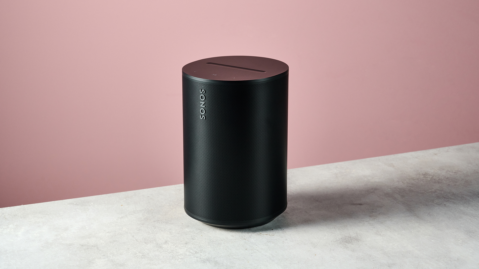 The Sonos Era 100 SL at a 3/4s angle in front of a pink background.